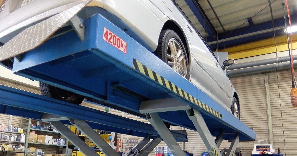 リフトで持ち上げられた整備工場内の車両