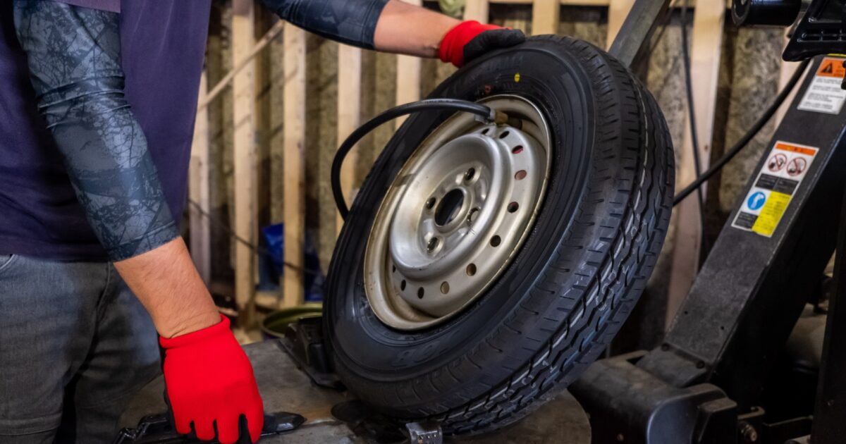 タイヤチェンジャーでホイールを整備する作業員