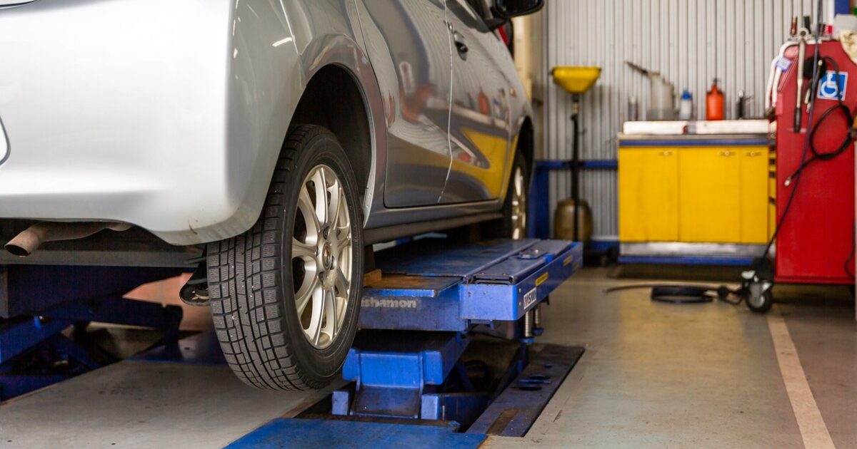 車両整備のためリフトに乗せられたシルバーのコンパクトカー