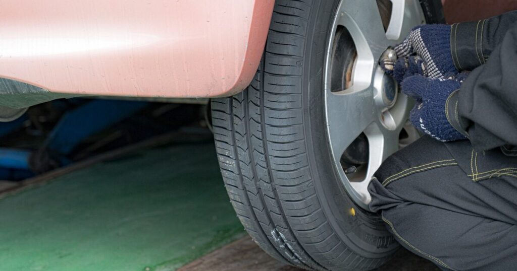 車のホイールナットを手締めする整備士の作業