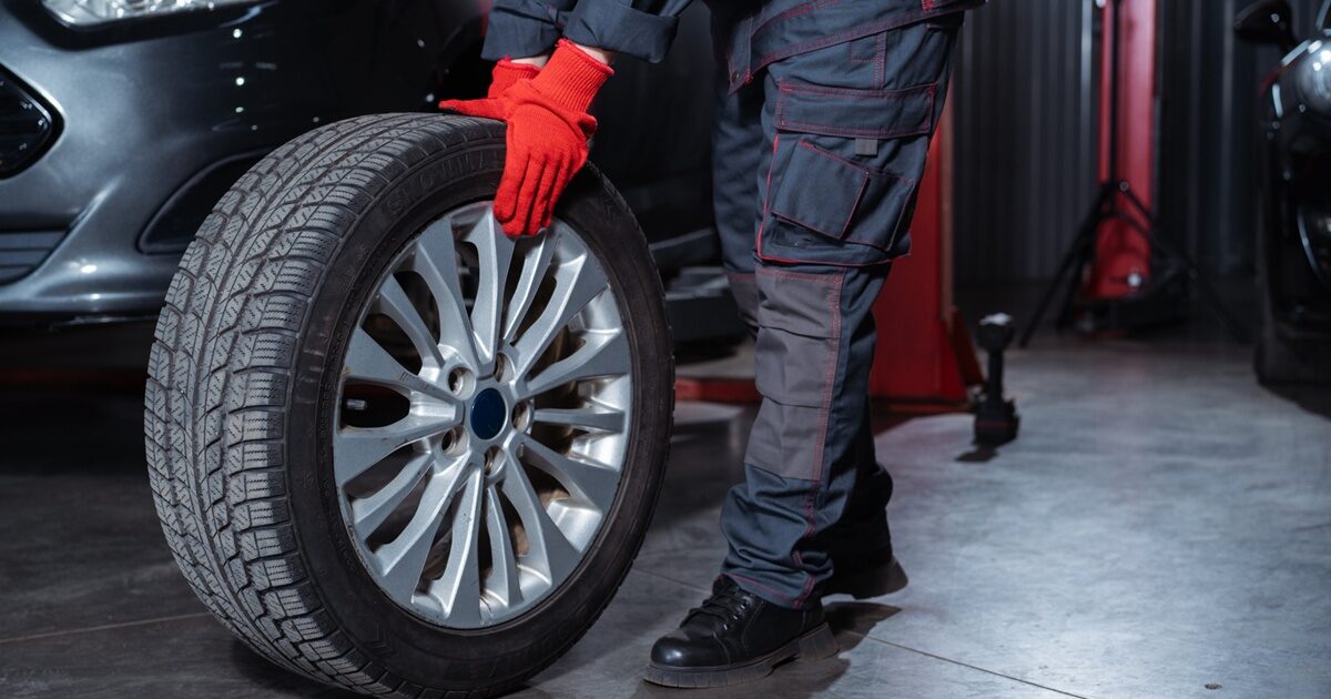 整備士がタイヤを持ち上げて作業する様子