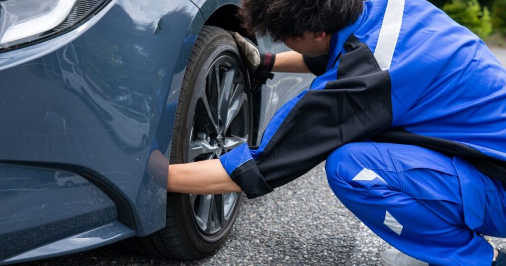 車のタイヤを点検する整備士